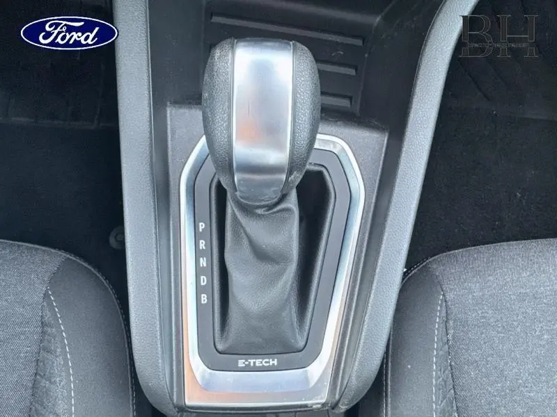 Le levier de vitesse automatique noir et argenté de la Renault Clio 1.6 E-Tech hybride, vu de dessus entre les sièges noirs.