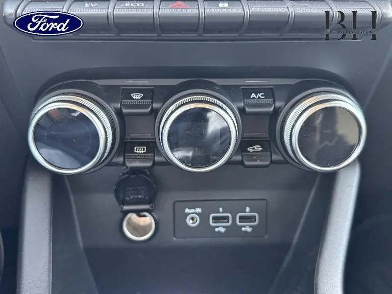 Gros plan sur les commandes de climatisation et les ports USB d'une Renault Clio gris titanium, version hybride 2021.