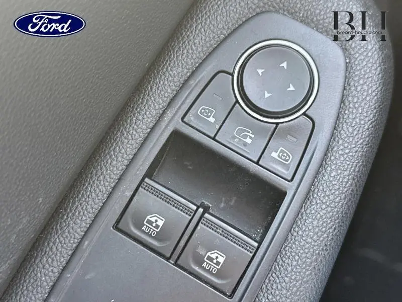 Gros plan sur les commandes de lève-vitres et rétroviseurs côté conducteur d'une Renault Clio gris Titanium 2021 hybride.