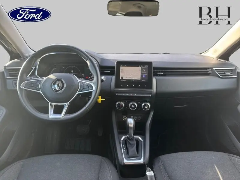 Vue intérieure frontale du tableau de bord et volant noir de la Renault Clio hybride gris Titanium 2021 avec écran tactile central.