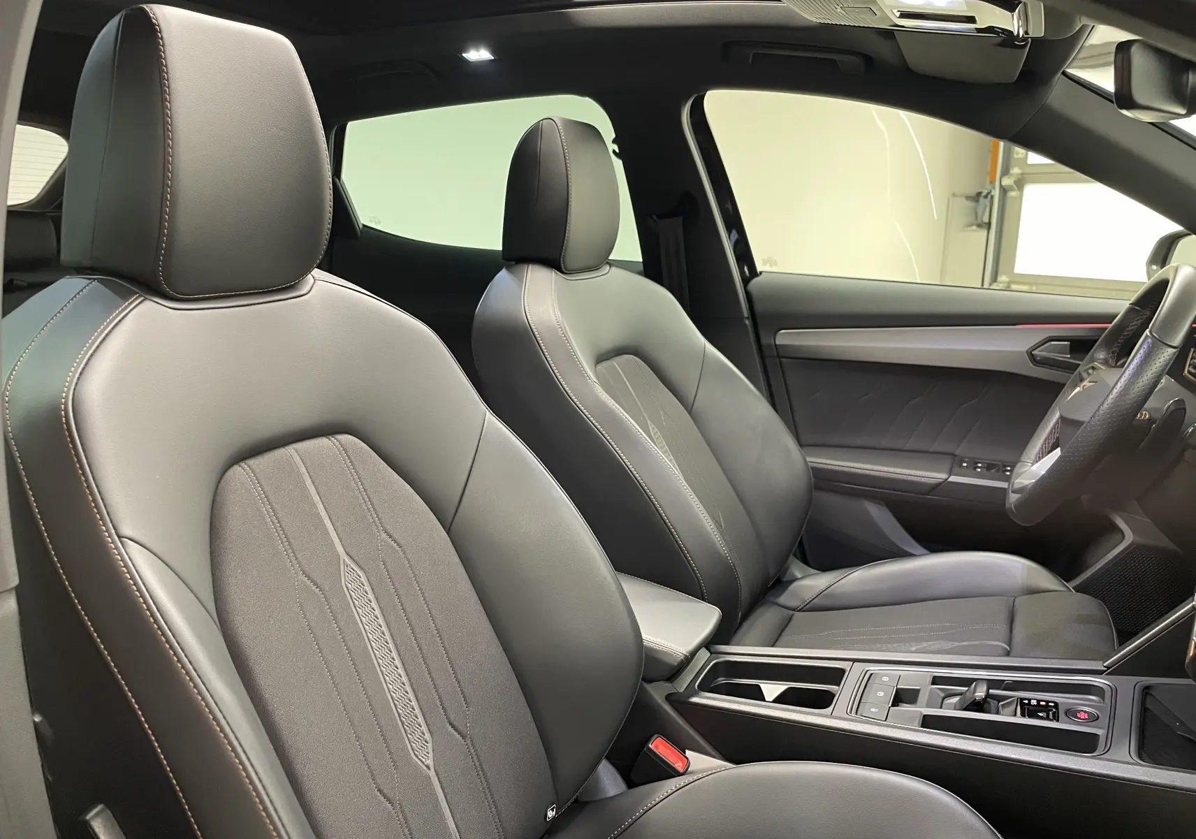 Vue intérieure côté droit du CUPRA Formentor 2023 avec sièges en cuir noir et surpiqûres marron, console centrale moderne.