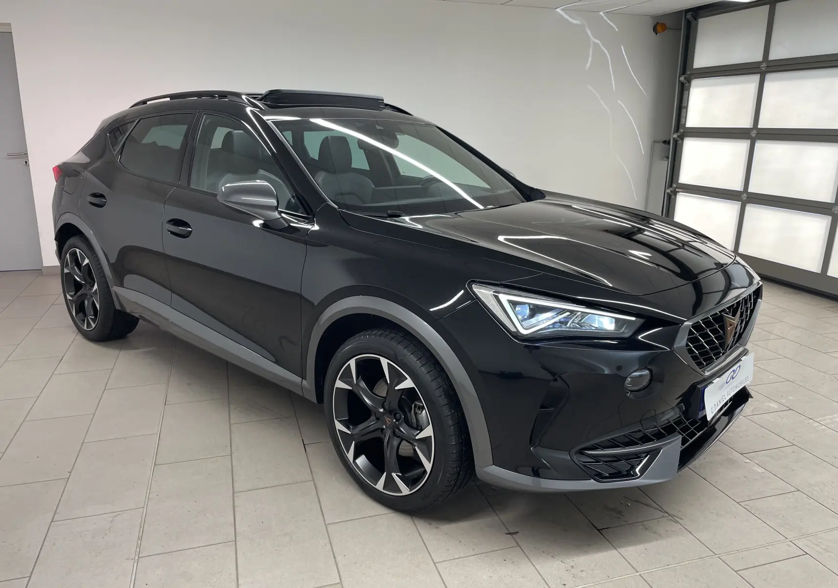 CUPRA Formentor 1.5 TSI 2023 en Noir Minuit, vue 3/4 avant droit, avec jantes noires et phares allumés.