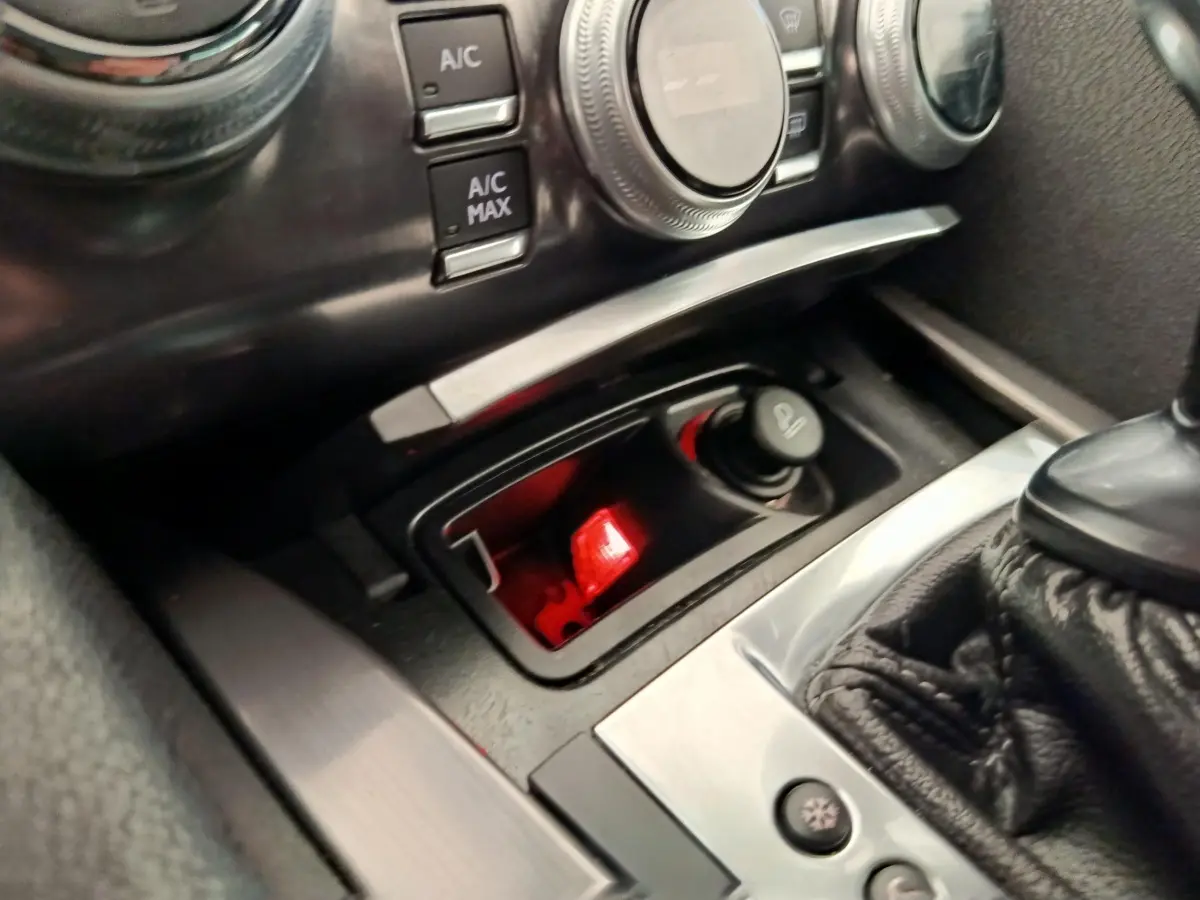 Gros plan intérieur sur la console centrale noire du DS5 avec commandes climatisation et prise allume-cigare éclairée rouge.