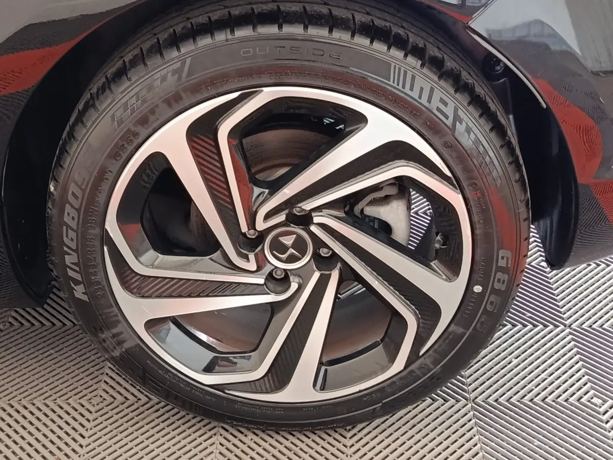 Gros plan sur la roue avant droite noire de la DS5 avec jante alliage bicolore au design moderne.