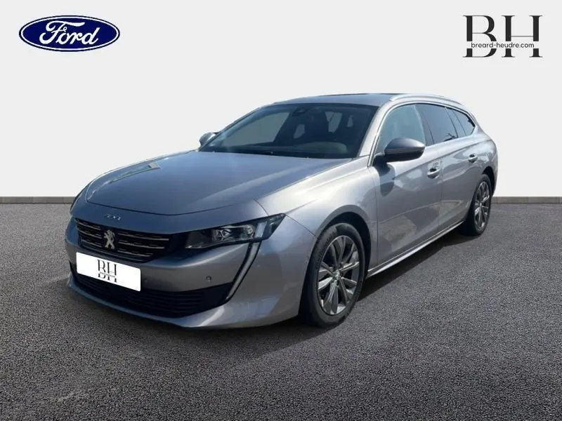Peugeot 508 SW gris Artense vue 3/4 avant droit avec jantes alliage et barres de toit visibles.