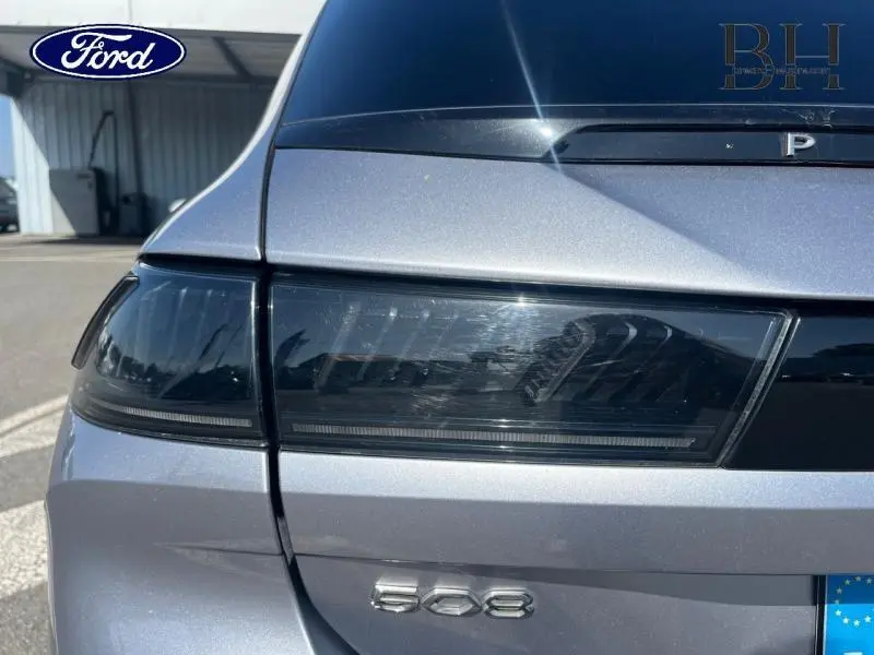 Gros plan sur le feu arrière gauche gris Artense d'une Peugeot 508 SW avec logo et monogramme visibles