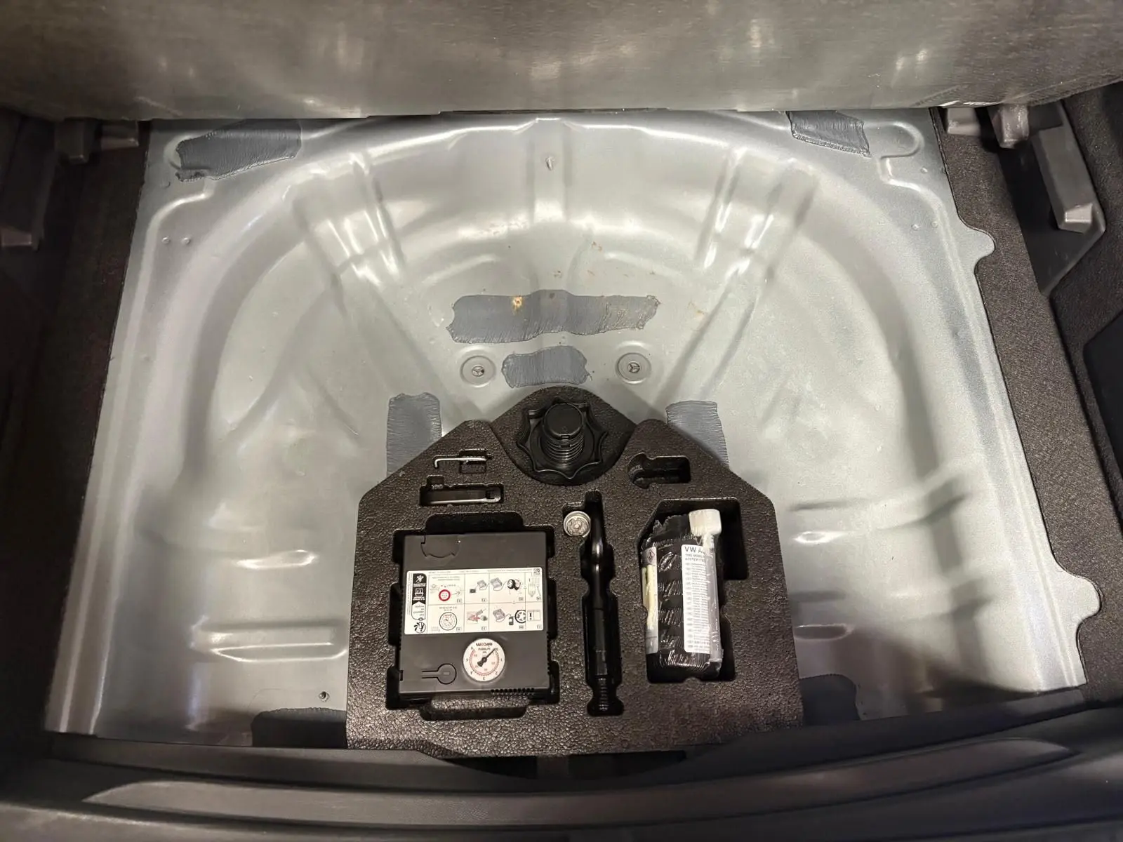 Coffre ouvert du CUPRA Formentor gris magnétique 2023 montrant la roue de secours et le kit de réparation.