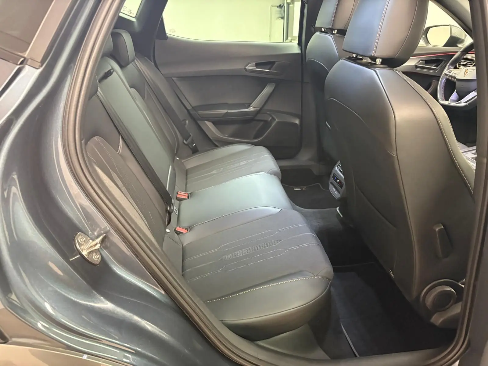 Vue intérieure côté gauche des sièges arrière en cuir noir du CUPRA Formentor gris magnétique 2023 avec détails de couture visibles.