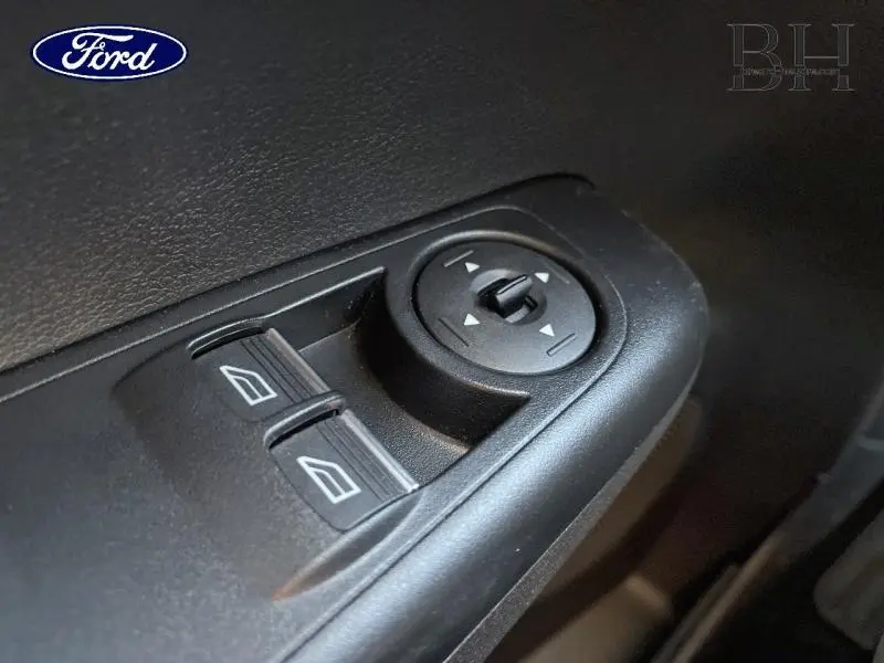 Gros plan sur les commandes de réglage des rétroviseurs et des vitres côté conducteur du Ford Tourneo Courier blanc Glacier.