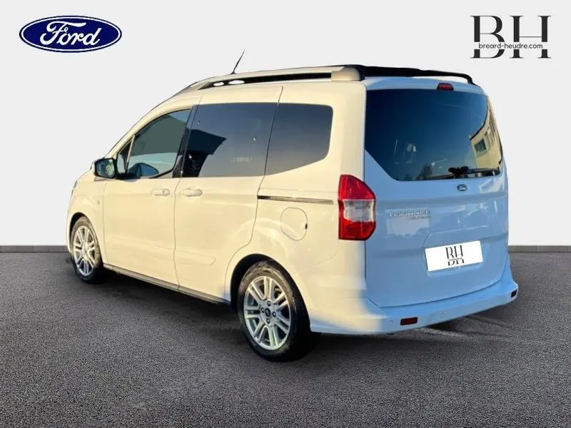 Vue 3/4 arrière droite du Ford Tourneo Courier blanc Glacier avec vitres arrière teintées et jantes alliage.