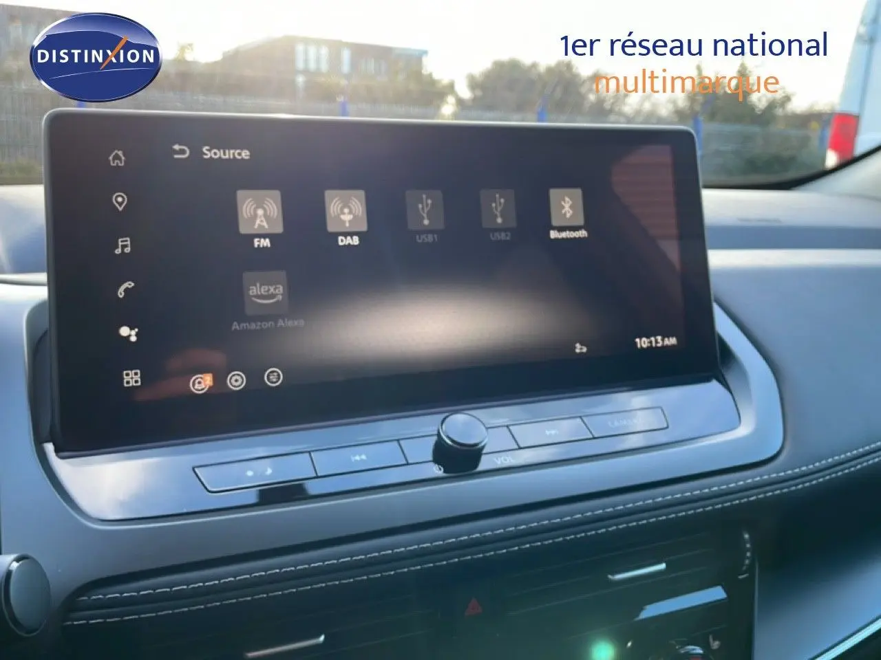 Écran tactile central du tableau de bord du Nissan Qashqai gris argile, affichant les sources audio connectées.