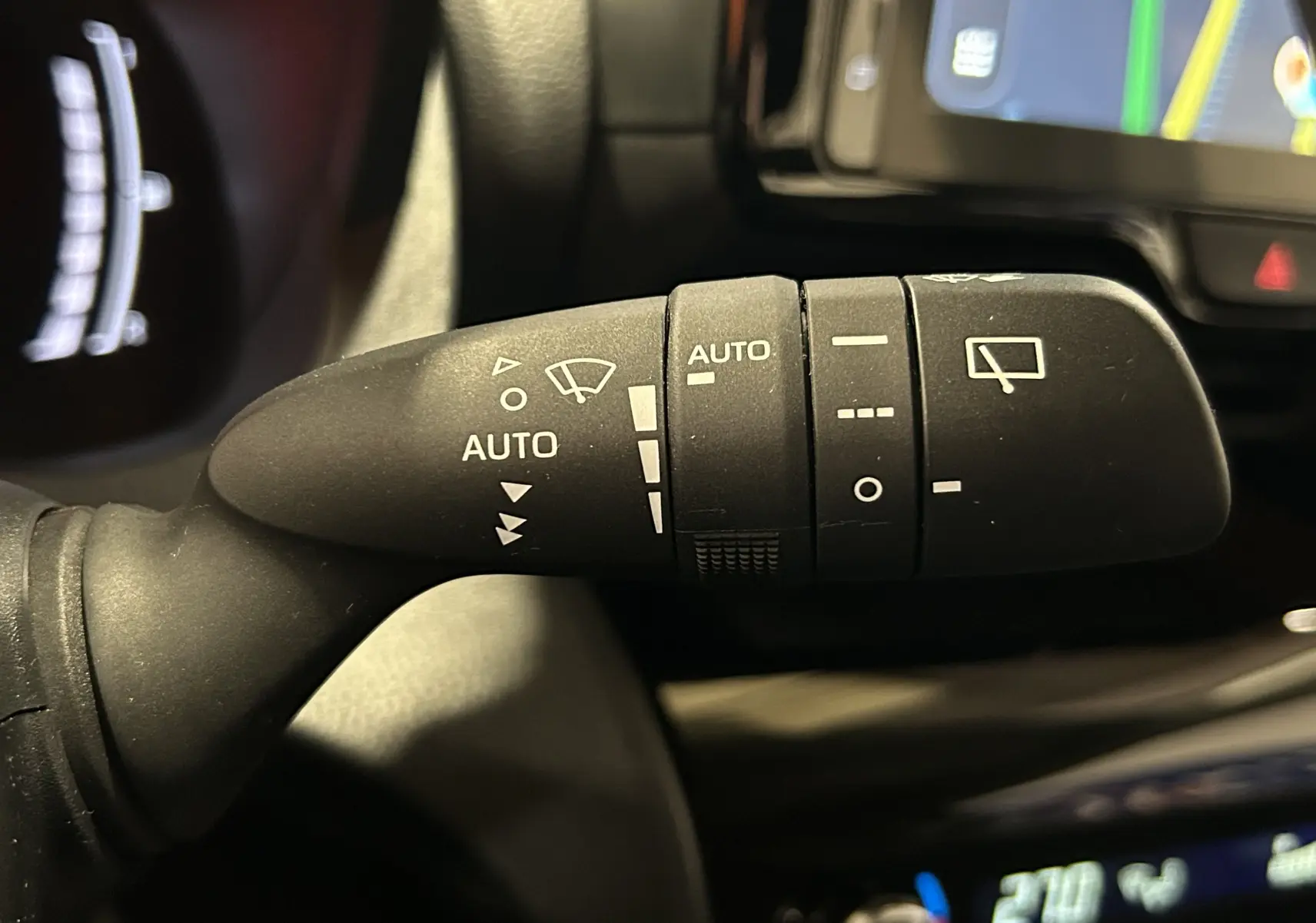 Gros plan sur la commande des essuie-glaces à droite du volant dans l’habitacle de la Toyota Yaris Cross gris minéral.