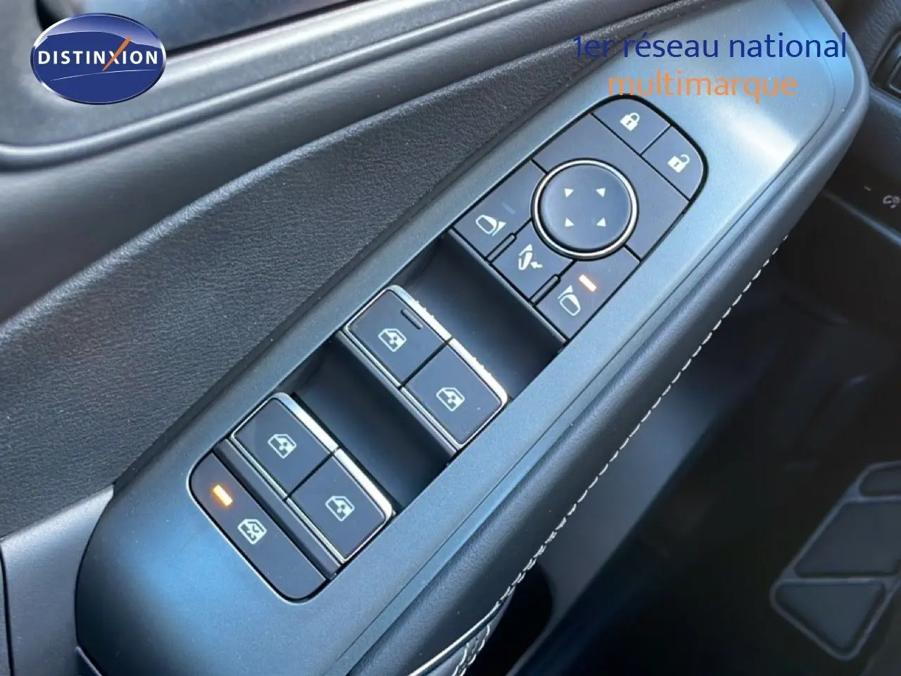 Gros plan sur les commandes des vitres côté conducteur du Nissan Qashqai gris argile métal, avec éclairage orange sur un bouton.