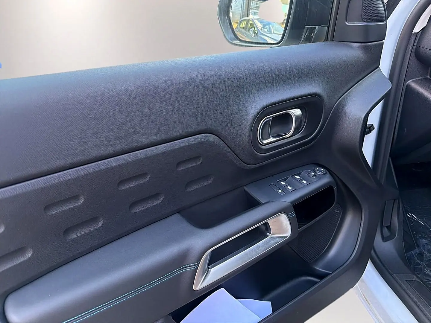 Vue intérieure côté conducteur de la porte noire avec poignée argentée et commandes des vitres du Citroën C5 Aircross blanc.