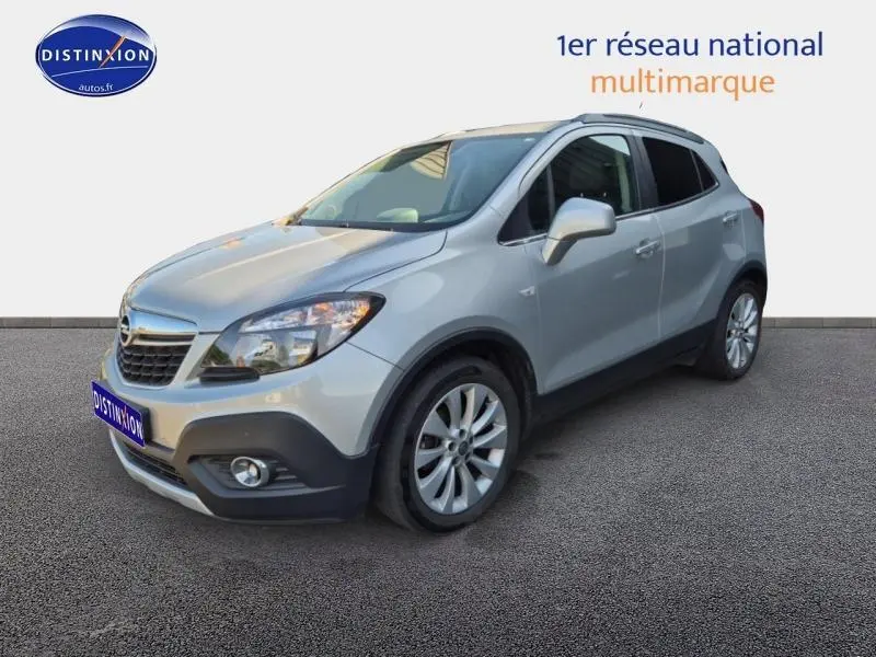 Opel Mokka gris astéroïde en 3/4 avant droit avec jantes alu et calandre chromée visible.