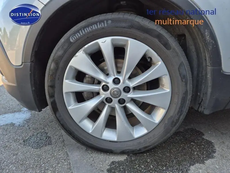 Gros plan sur la roue avant gauche grise de l’Opel Mokka 2016 avec jante alu et logo Opel au centre.