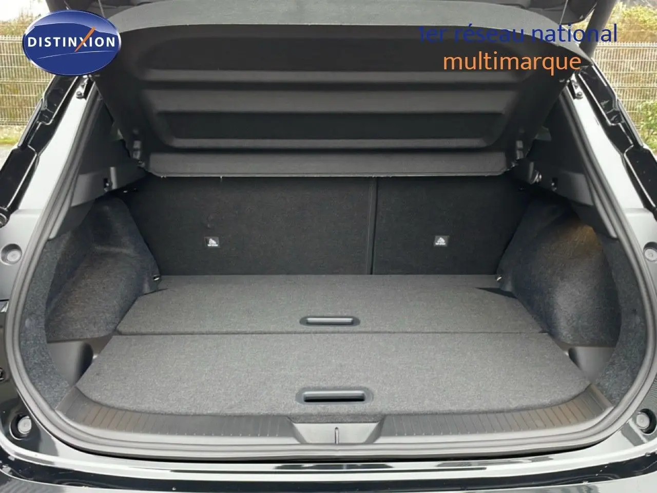 Coffre ouvert du Nissan Qashqai noir perle métal, vue arrière montrant un espace de chargement plat et spacieux.