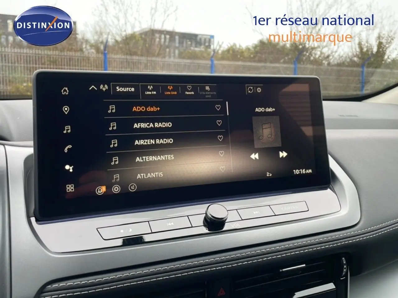 Écran tactile central du Nissan Qashqai 2025, affichant les stations radio DAB+, avec tableau de bord gris et surpiqûres blanches.