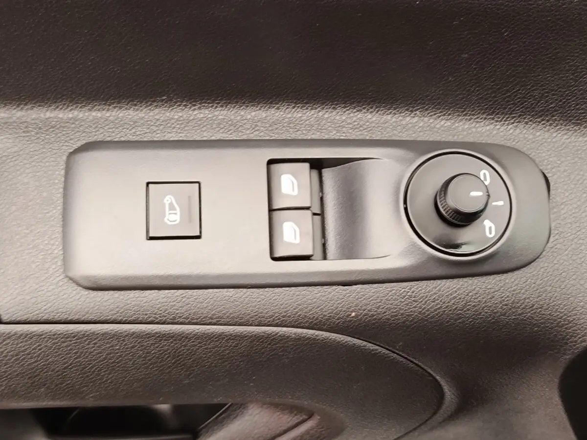 Gros plan sur les commandes de réglage des rétroviseurs et des vitres électriques côté conducteur du Peugeot Partner blanc.