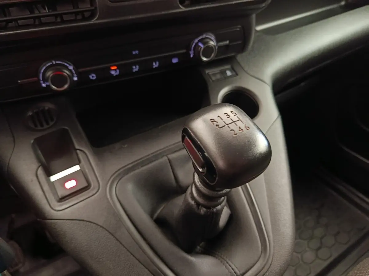 Gros plan sur le levier de vitesses manuel noir du Peugeot Partner 2022 avec console centrale et commandes de climatisation.