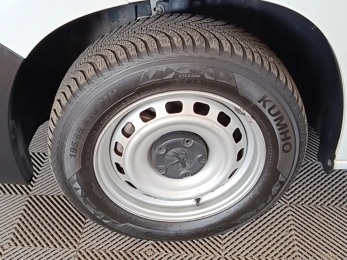 Gros plan sur la roue avant droite en jante acier du Peugeot Partner blanc, montrant le pneu Kumho 4 saisons.