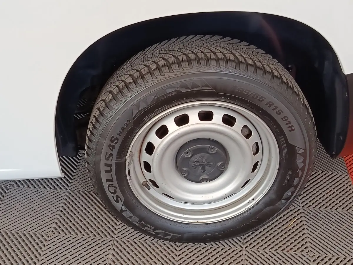 Gros plan sur la roue arrière droite en jante acier argentée du Peugeot Partner blanc de 2022.