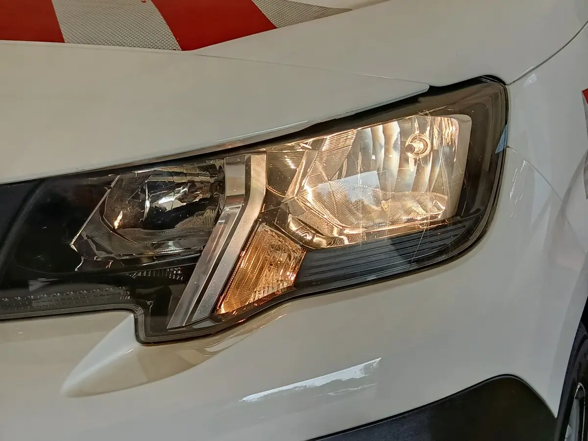Gros plan sur le phare avant droit blanc du Peugeot Partner 2022, mettant en valeur les détails du bloc optique.