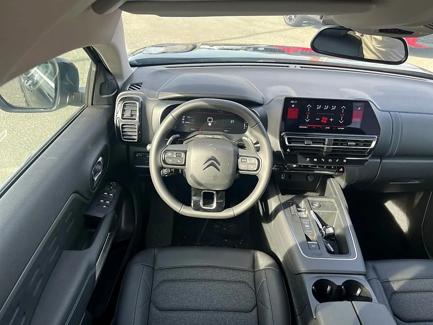 Vue intérieure avant du Citroën C5 Aircross 2025 noir, tableau de bord moderne avec écran tactile et volant cuir multifonction.
