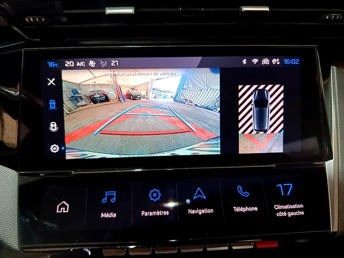 Écran tactile central de la Peugeot 308 PHEV 180 GT montrant la caméra de recul et l'aide au stationnement arrière.