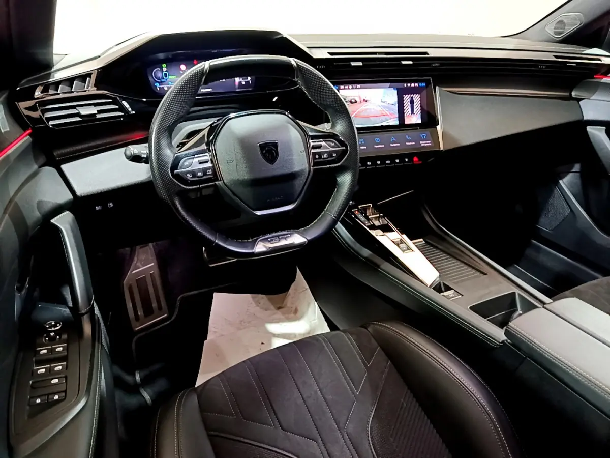 Intérieur de la Peugeot 308 PHEV 180 GT 2022, vue du poste de conduite avec volant compact et écran tactile central.