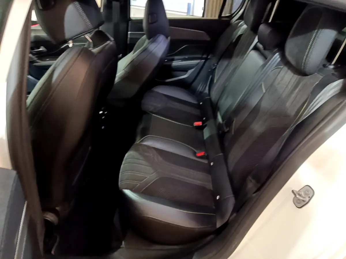 Vue côté droit de l'habitacle arrière d'une Peugeot 308 PHEV 180 E-EAT8 GT blanche avec sièges noirs en cuir et tissu.