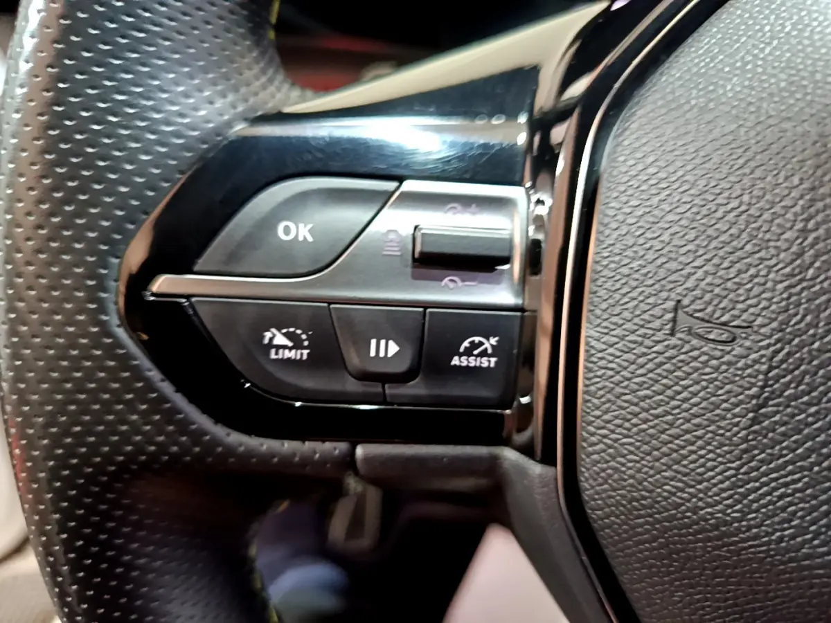 Gros plan sur les commandes gauche du volant en cuir perforé de la Peugeot 308 PHEV 180 E-EAT8 GT 2022.