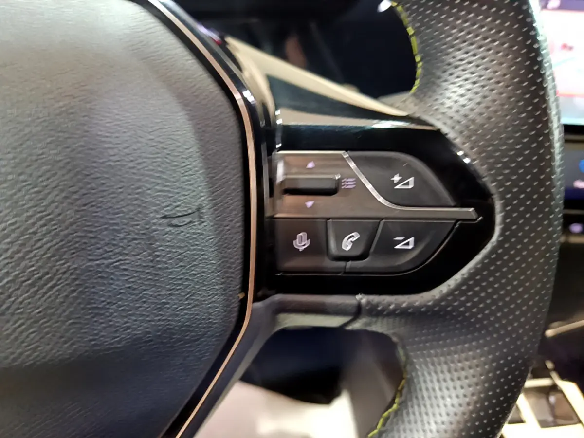 Gros plan sur les commandes du volant en cuir perforé de la Peugeot 308 PHEV 180 E-EAT8 GT blanche, côté droit.