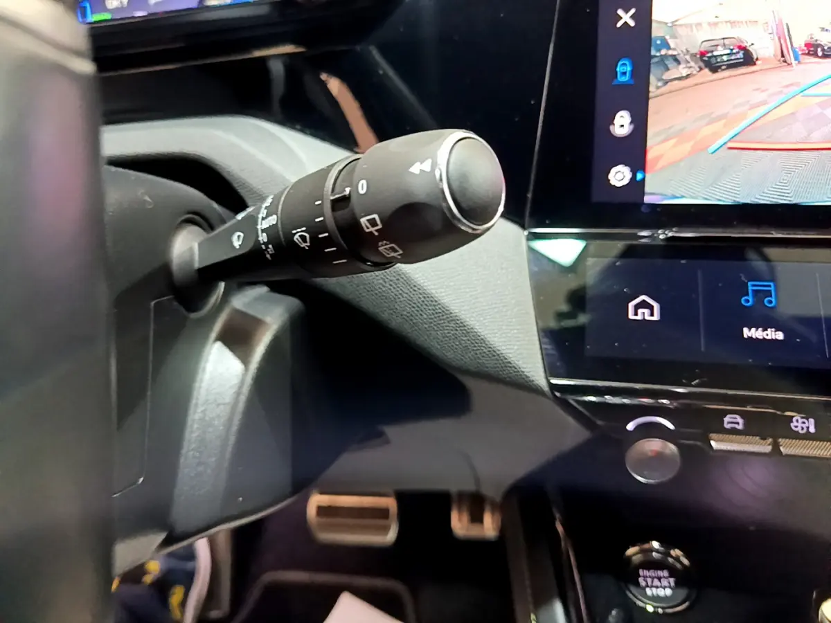 Gros plan sur la commande d’essuie-glace et l’écran tactile du tableau de bord de la Peugeot 308 PHEV blanche de 2022.