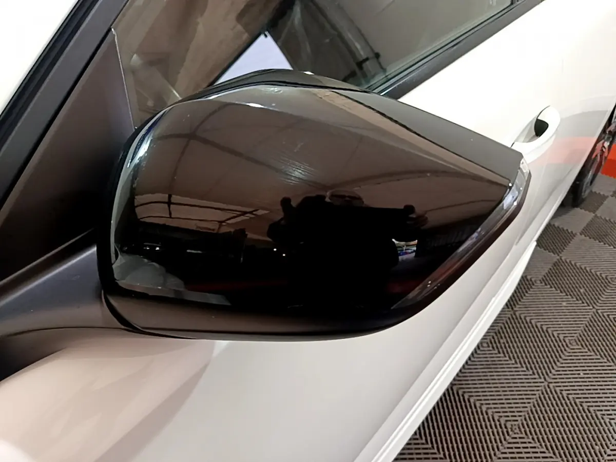 Rétroviseur noir côté gauche d'une Peugeot 308 PHEV 180 E-EAT8 GT blanche vue en gros plan depuis l'avant