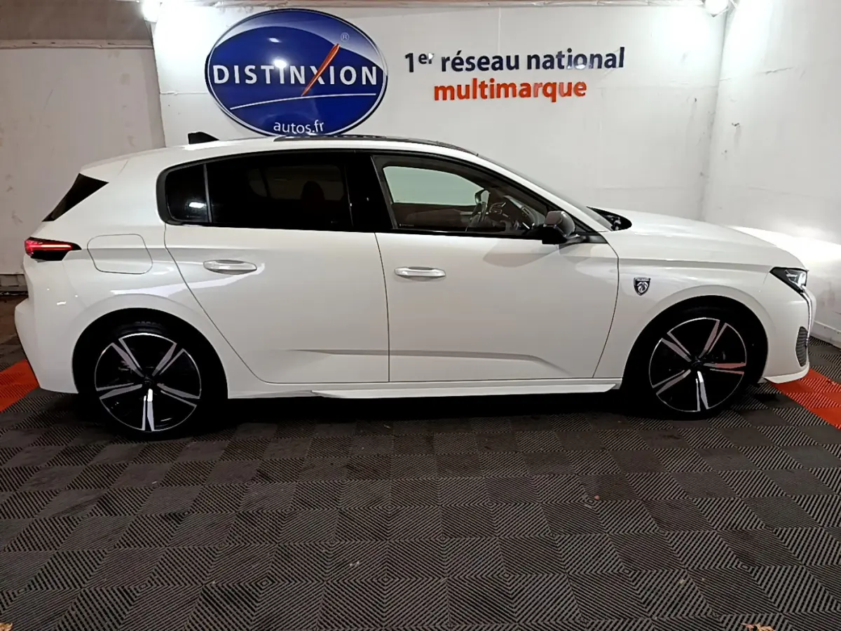 Peugeot 308 PHEV 180 E-EAT8 GT blanc vue de profil côté gauche, jantes noires à inserts argentés.