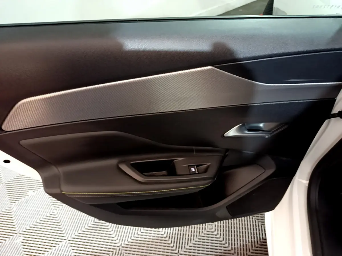 Vue rapprochée de la porte côté gauche blanche d'une Peugeot 308 PHEV 180 E-EAT8 GT avec garniture noire et insert gris.
