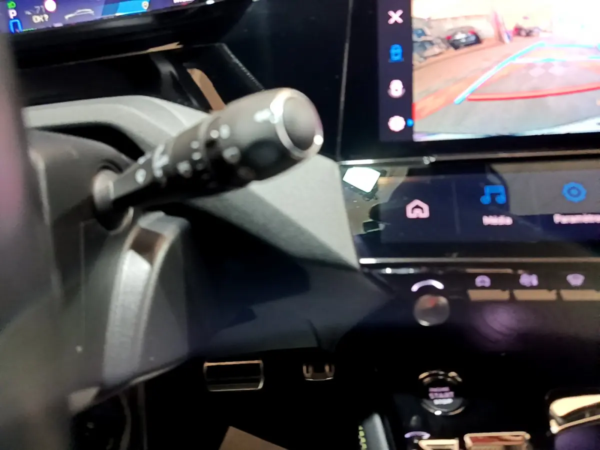 Détail intérieur montrant la commande au volant et l'écran tactile avec caméra de recul de la Peugeot 308 PHEV 180 GT.