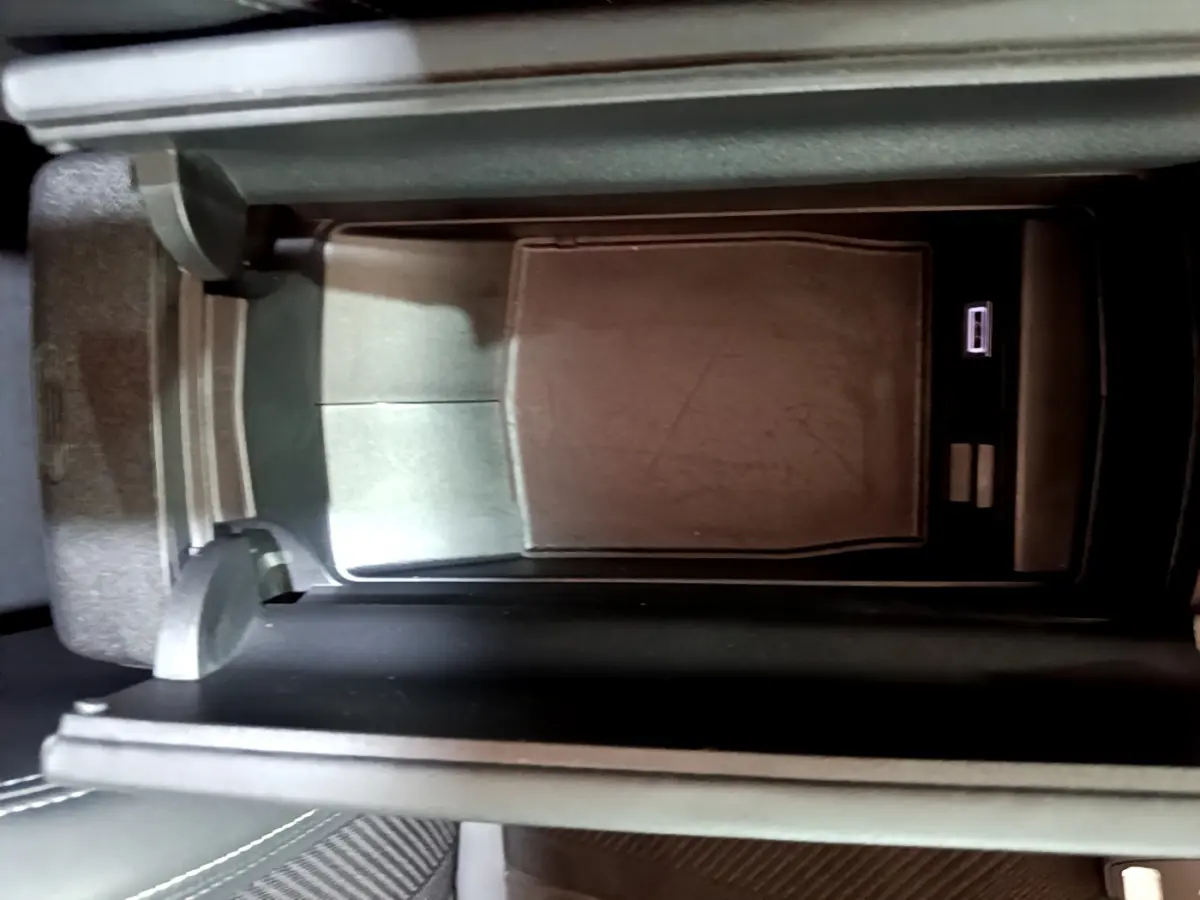 Gros plan sur la console centrale noire de la Peugeot 308 PHEV 180 E-EAT8 GT, avec compartiment ouvert et port USB visible.