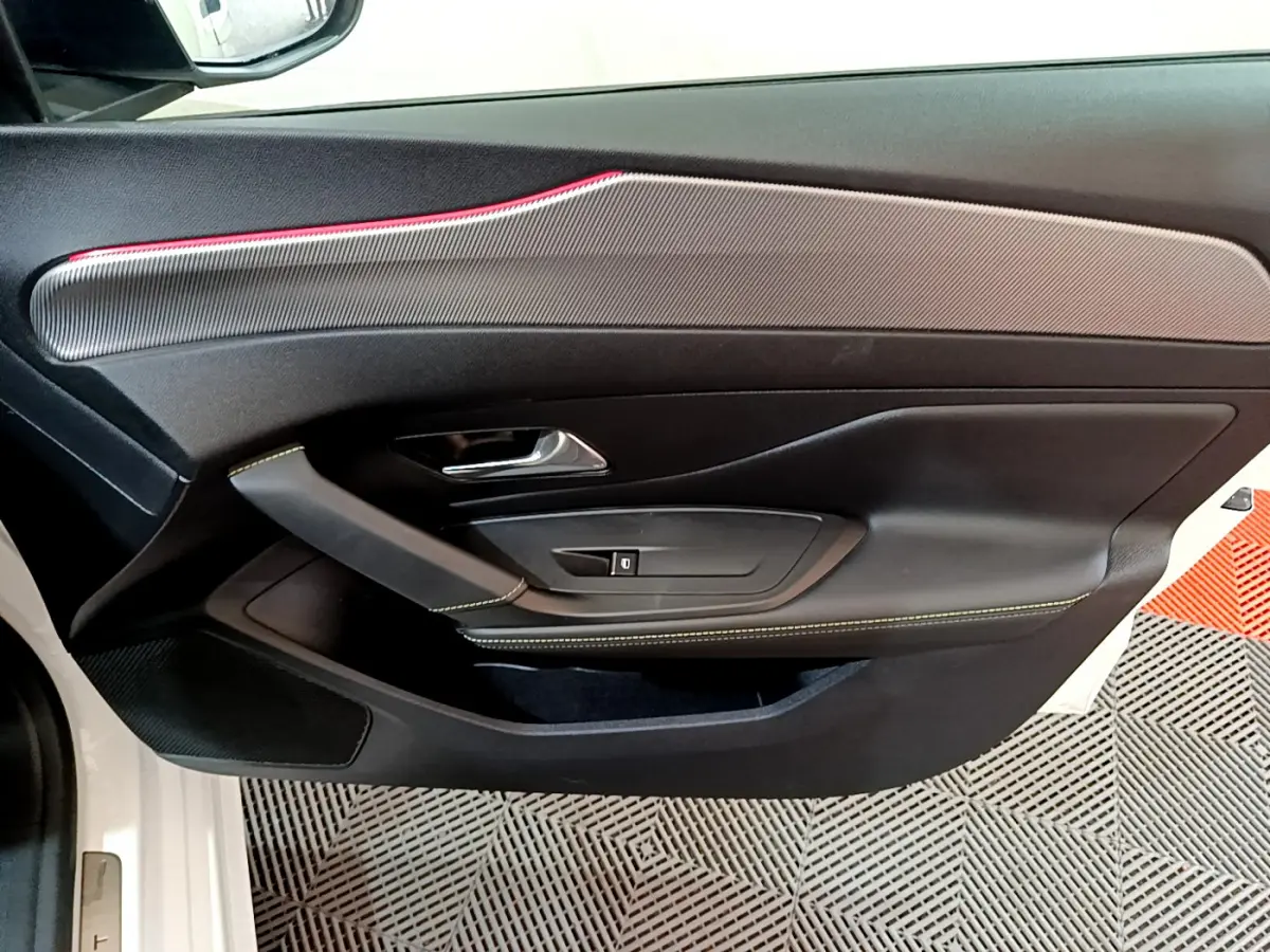 Gros plan sur la porte côté gauche blanche de la Peugeot 308 PHEV 180 E-EAT8 GT avec surpiqûres vertes et insert décoratif gris.