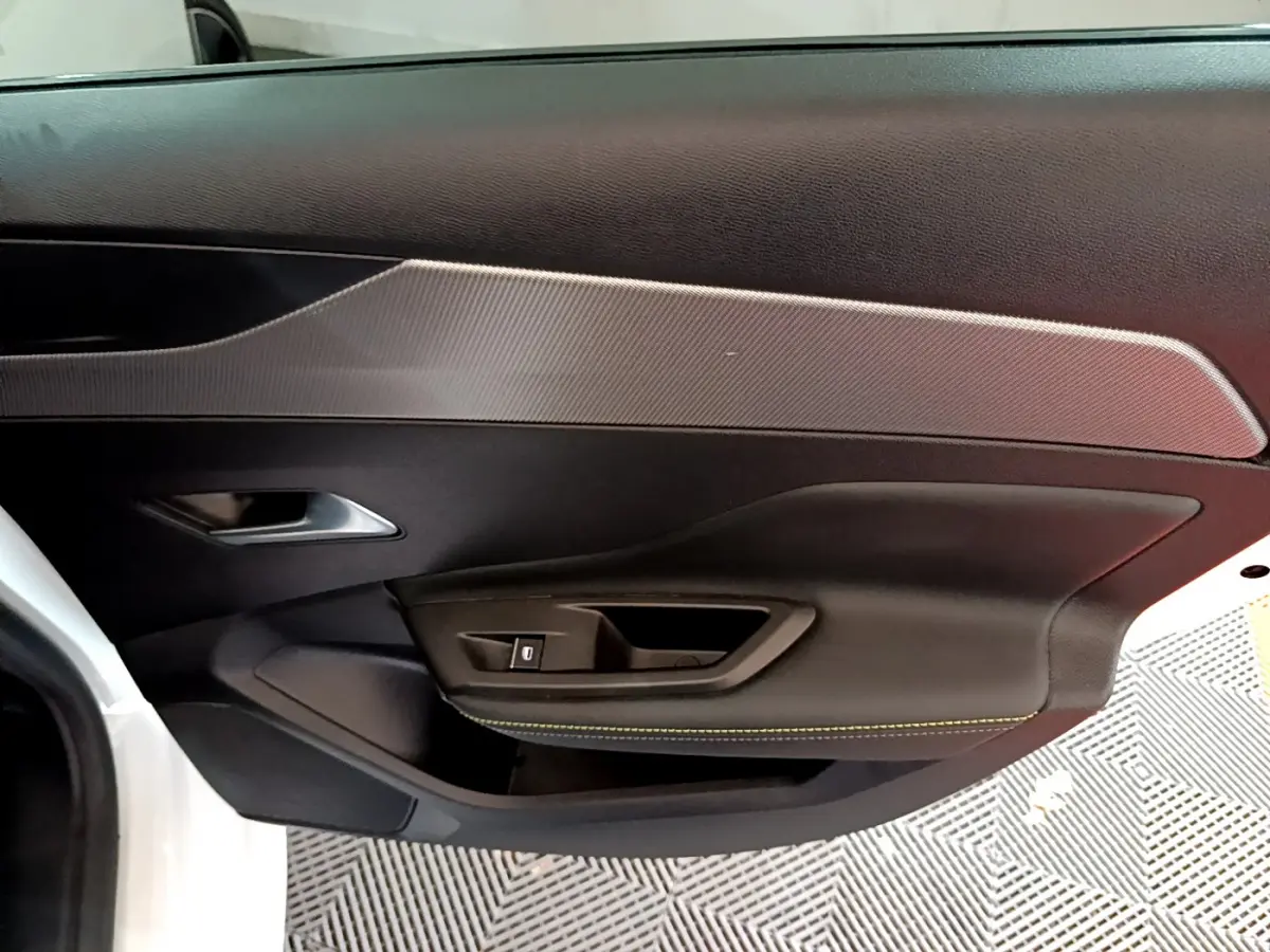 Gros plan sur la porte intérieure côté gauche de la Peugeot 308 PHEV 180 GT blanche avec surpiqûres jaunes.