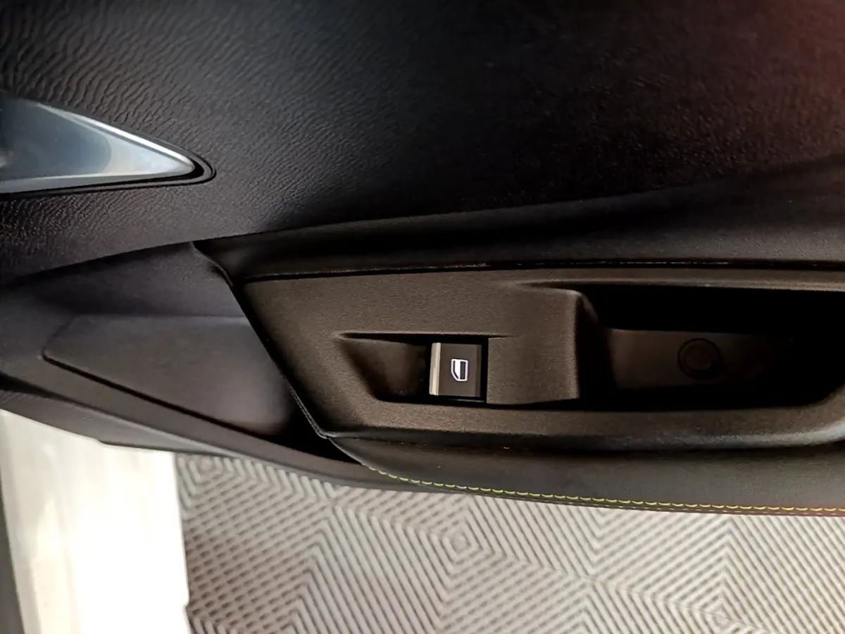 Bouton de commande de lève-vitre sur la porte intérieure noire d'une Peugeot 308 PHEV 180 E-EAT8 GT blanche.