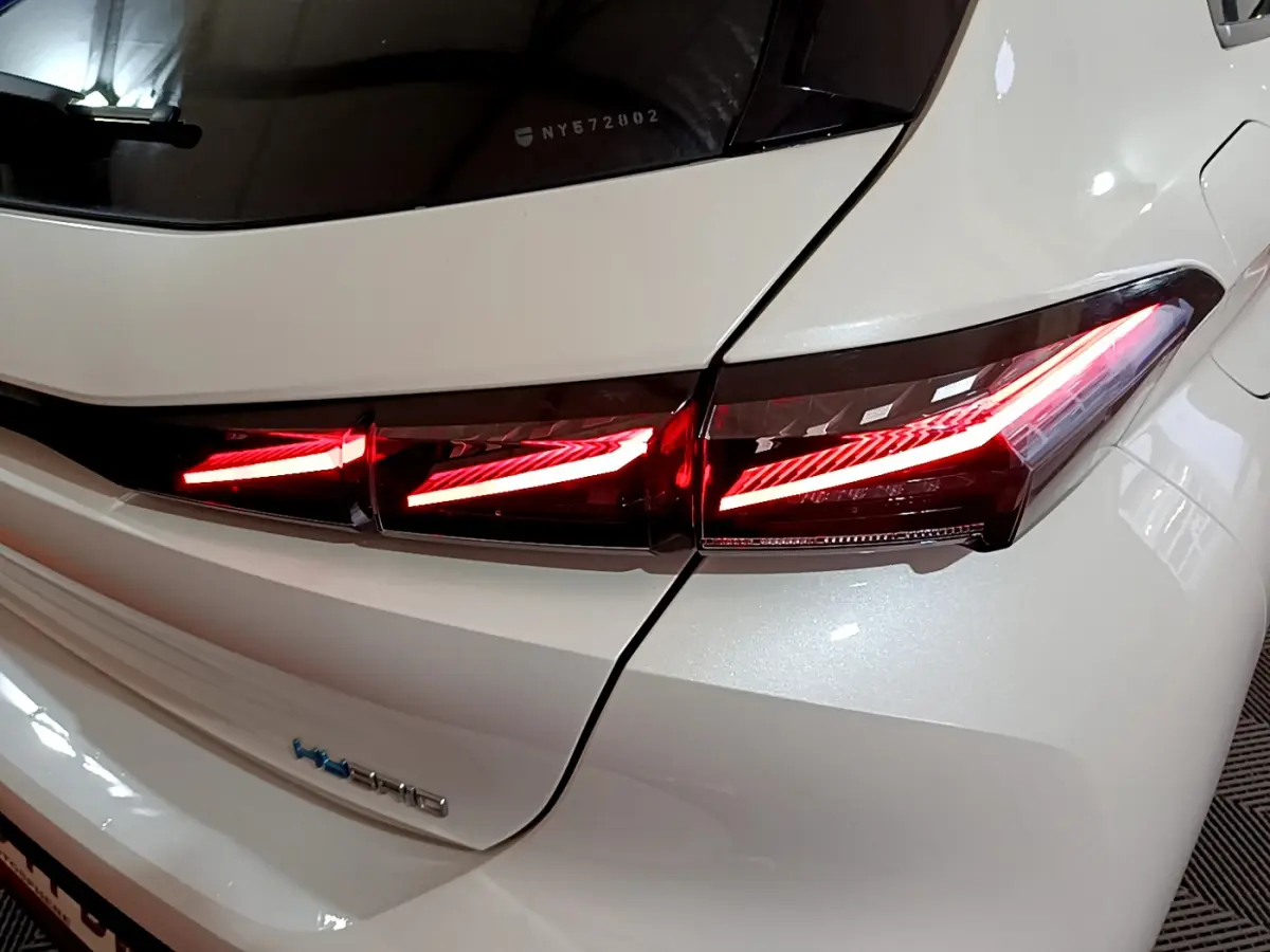 Gros plan sur le feu arrière droit allumé d'une Peugeot 308 PHEV 180 E-EAT8 GT blanche, soulignant ses lignes modernes.
