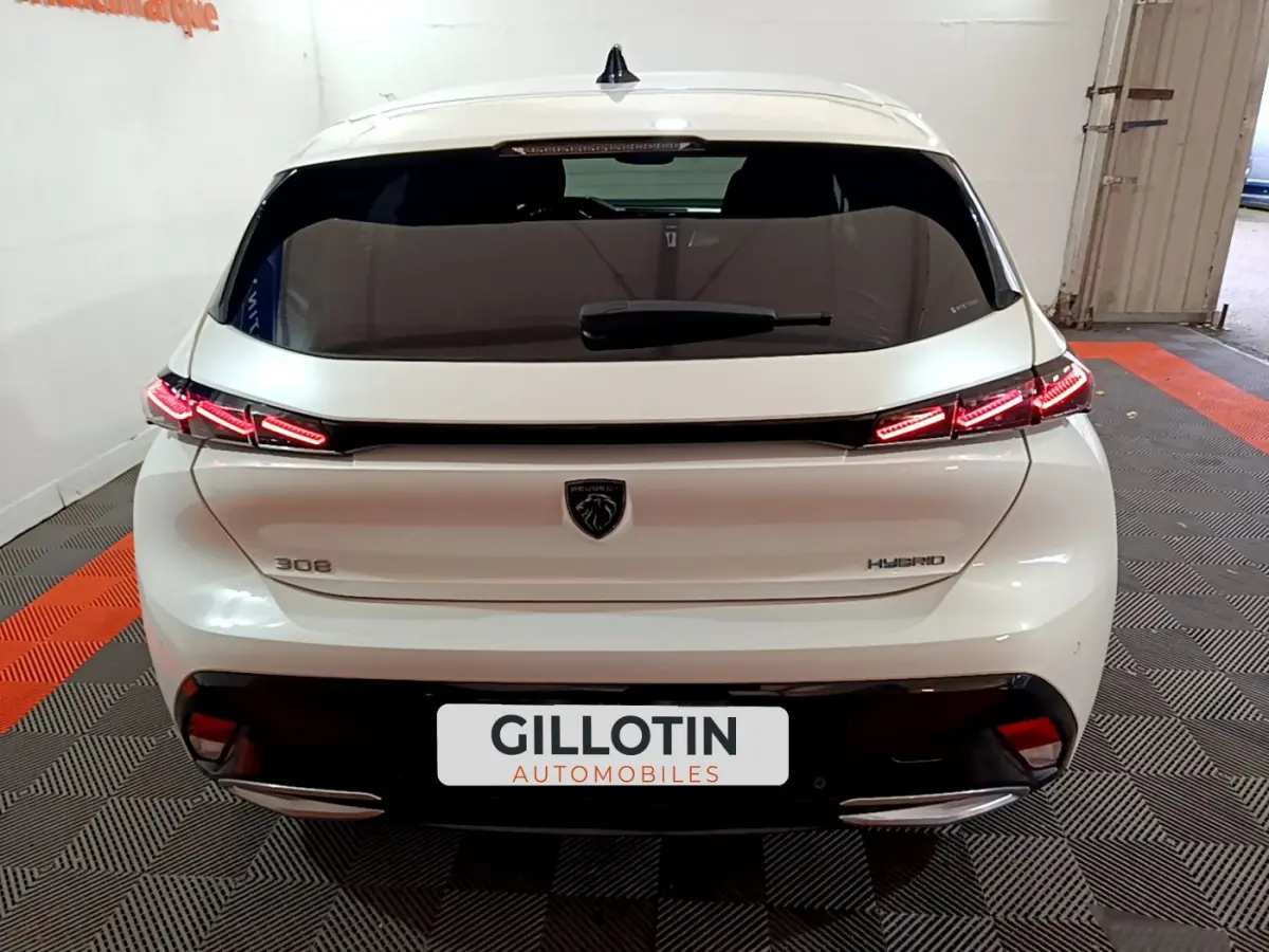 Vue arrière d'une Peugeot 308 PHEV 180 E-EAT8 GT blanche avec feux LED distinctifs et logo lion central.