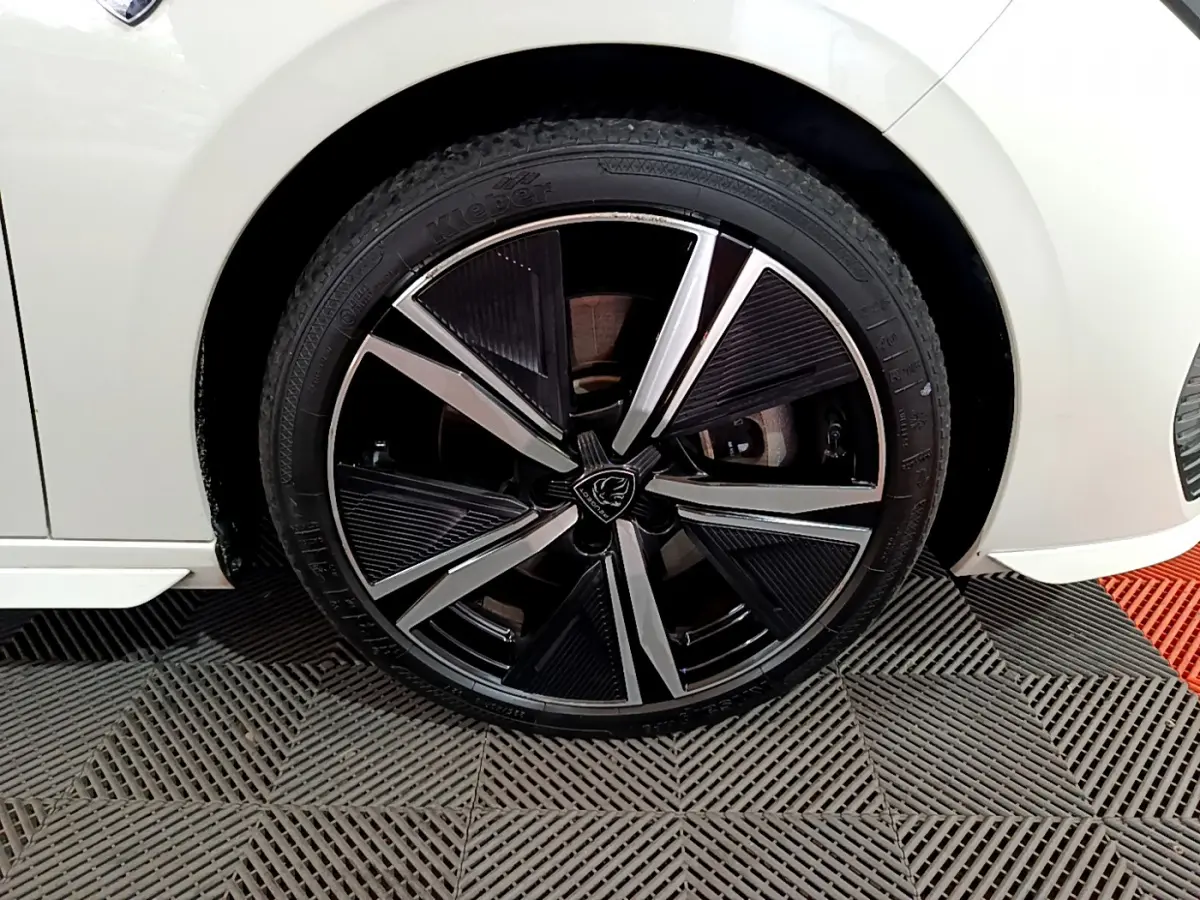 Gros plan sur la roue avant gauche de la Peugeot 308 PHEV 180 E-EAT8 GT blanche, jante alliage noire et argentée.
