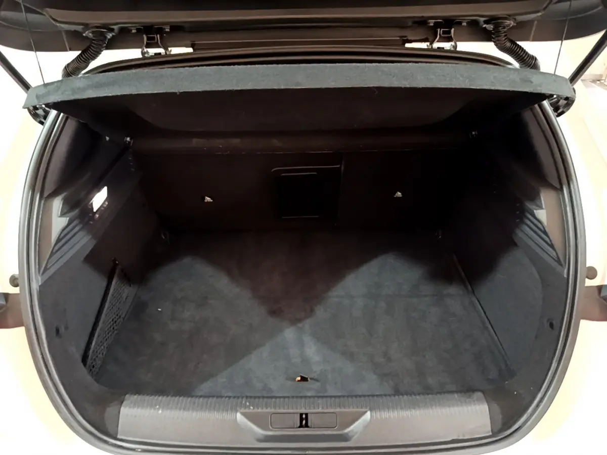 Coffre ouvert de la Peugeot 308 PHEV 180 E-EAT8 GT blanc, montrant un espace de chargement propre et spacieux.