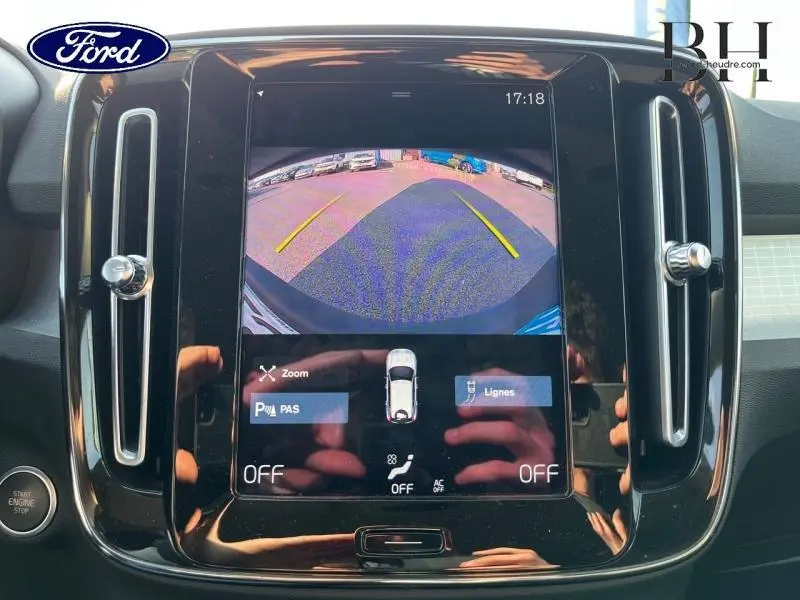 Écran tactile central affichant la caméra de recul du Volvo XC40 gris Glacier, avec commandes et aérateurs latéraux.