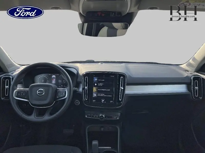 Vue intérieure avant du Volvo XC40 T5 Recharge gris Glacier, tableau de bord avec écran tactile central et volant cuir multifonctions.