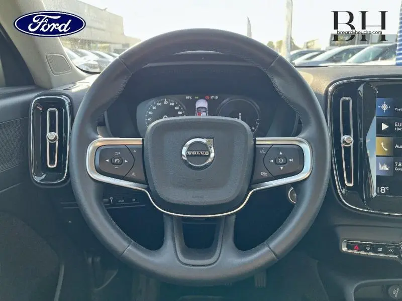 Vue intérieure centrée sur le volant cuir noir du Volvo XC40 T5 Recharge gris Glacier avec tableau de bord numérique.