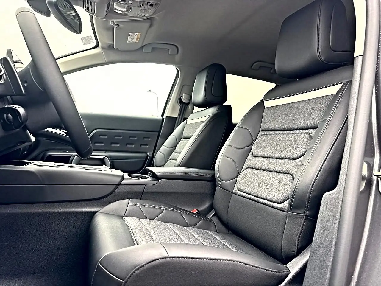 Intérieur avant du Citroën C5 Aircross 2025, sièges cuir et tissu gris, vue côté conducteur avec accoudoir central.